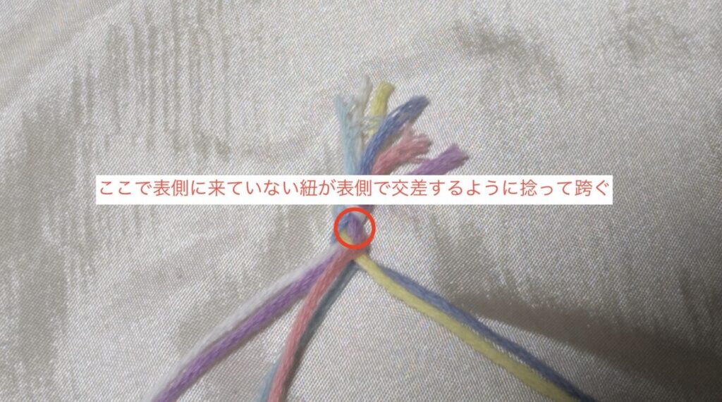 7:6で動かした反対の端の2本で今度は今真ん中に来ている2本を跨ぐように交差させ、3組の真ん中に来るようにします(写真では白・紫の2本で跨いでます)